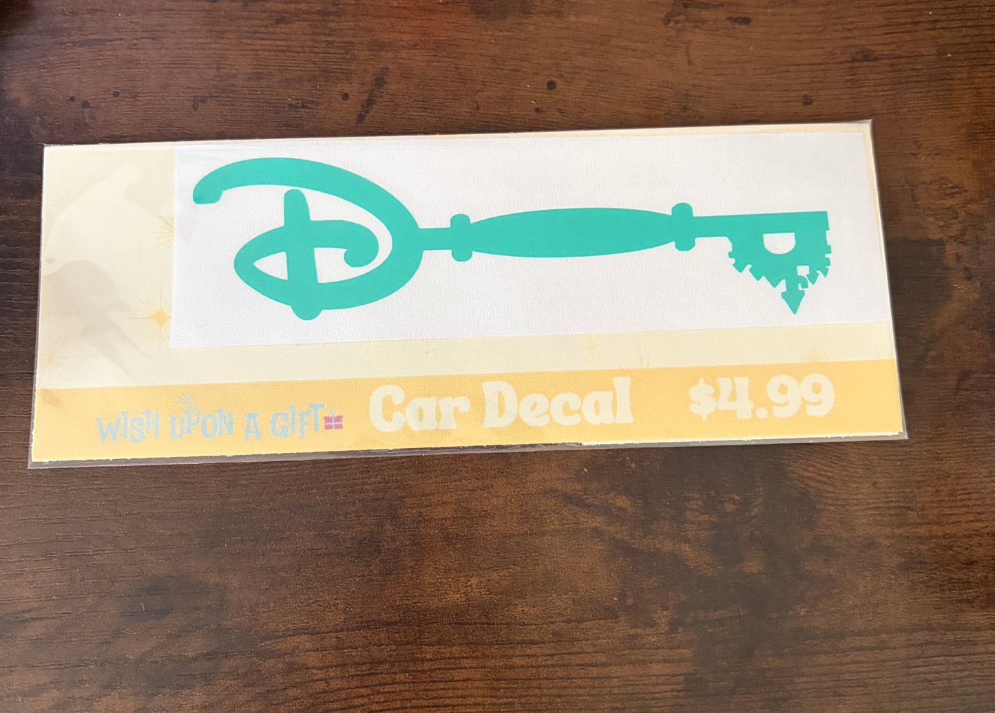 Car decal packaging with graphics of disney key and text on a wooden surface