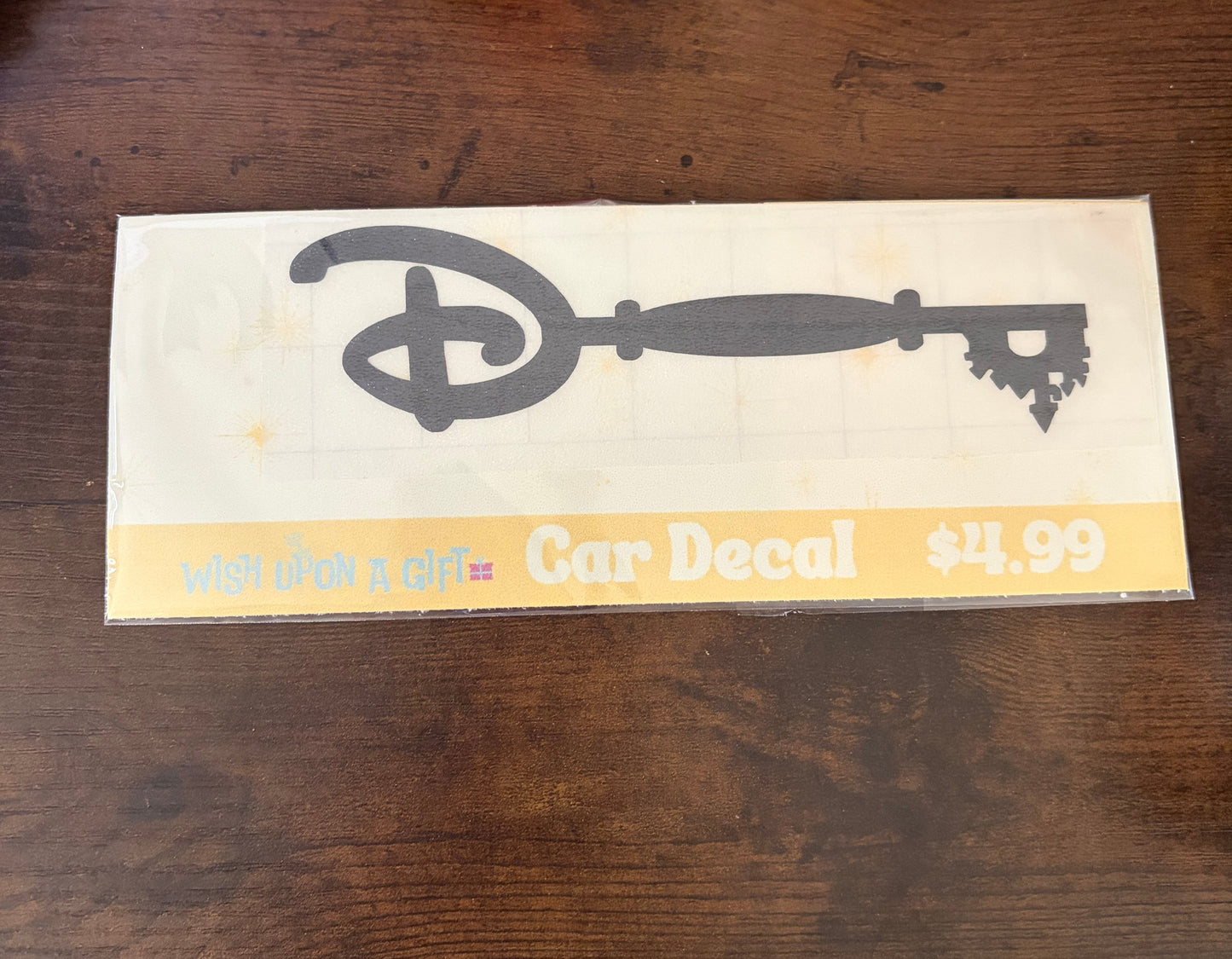 Car decal packaging with graphics of disney key and text on a wooden surface