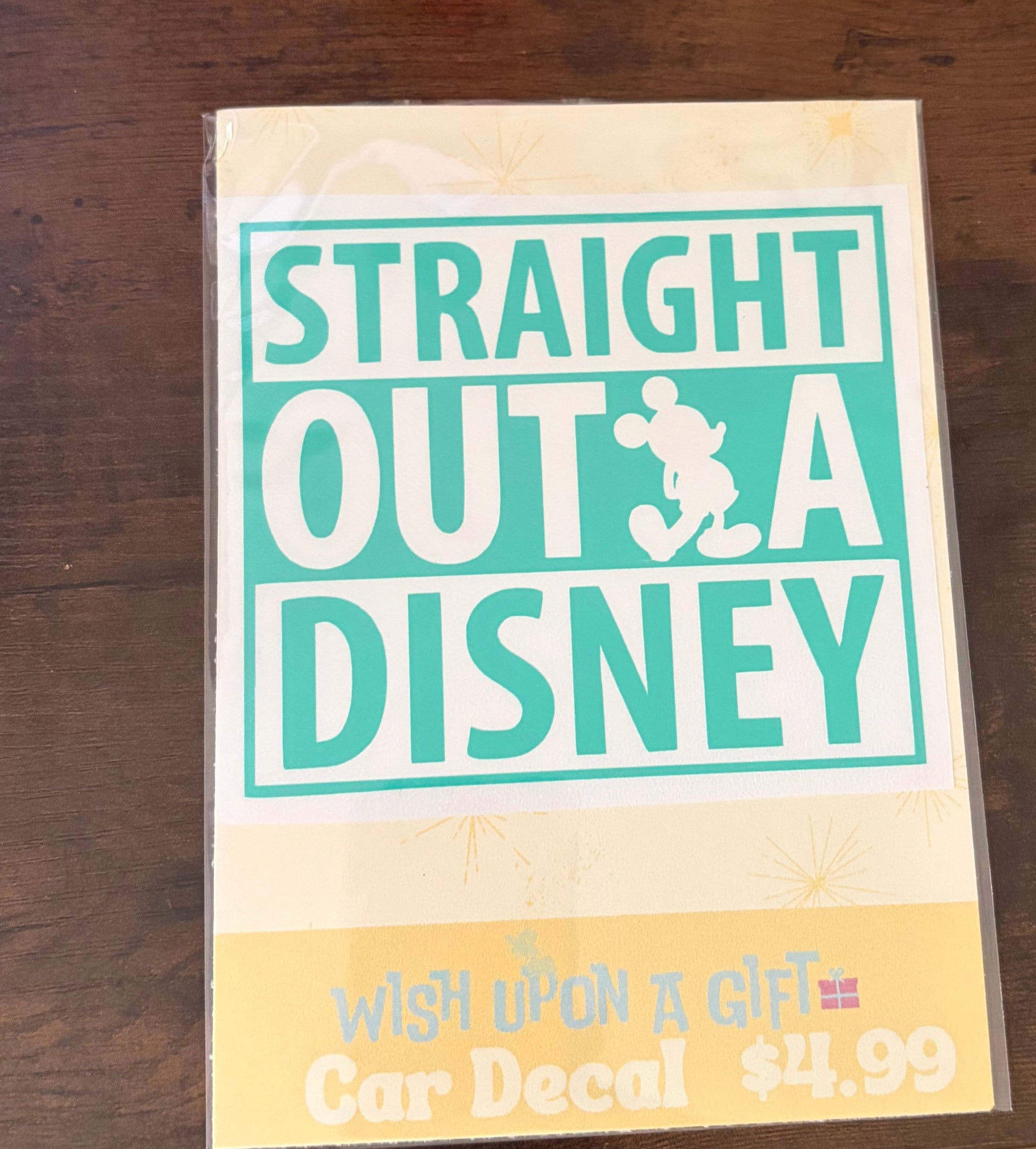 Product packaging with 'Straight Outta Disney' decal on a wooden surface.