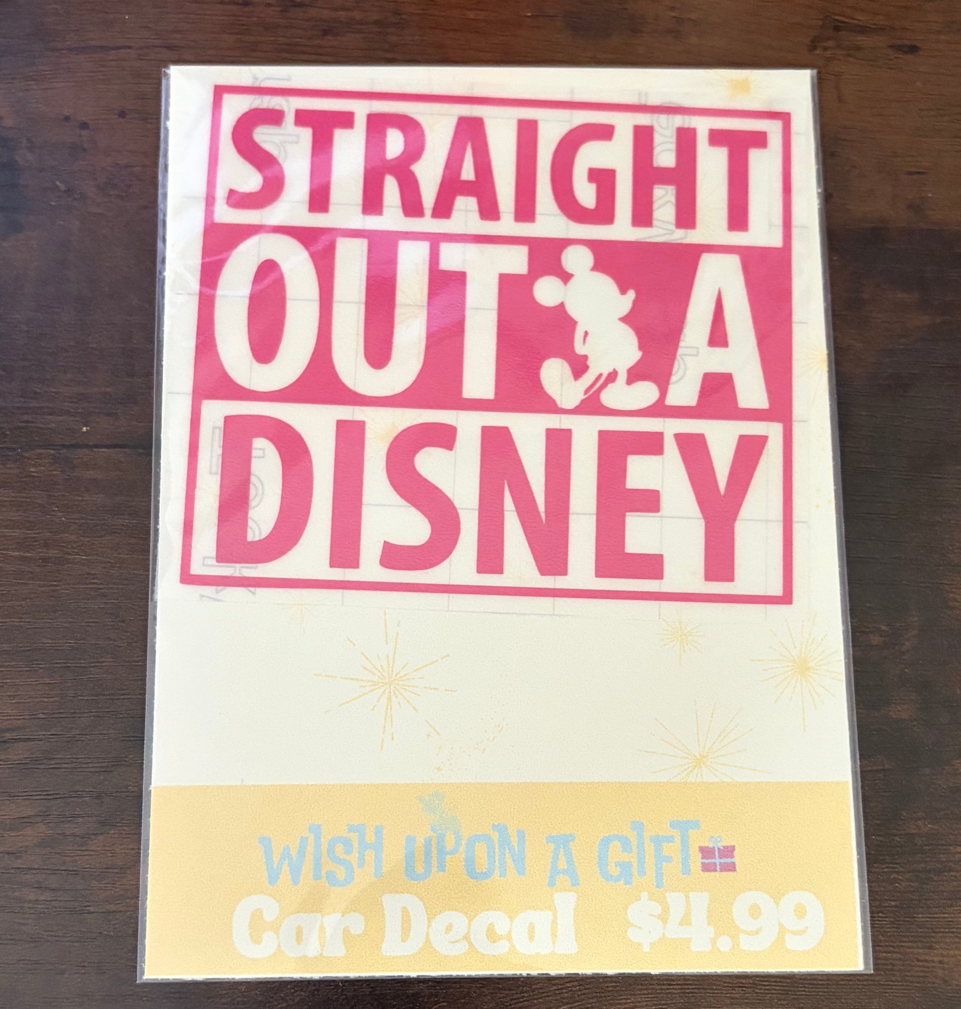 Product packaging with 'Straight Outta Disney' decal on a wooden surface.
