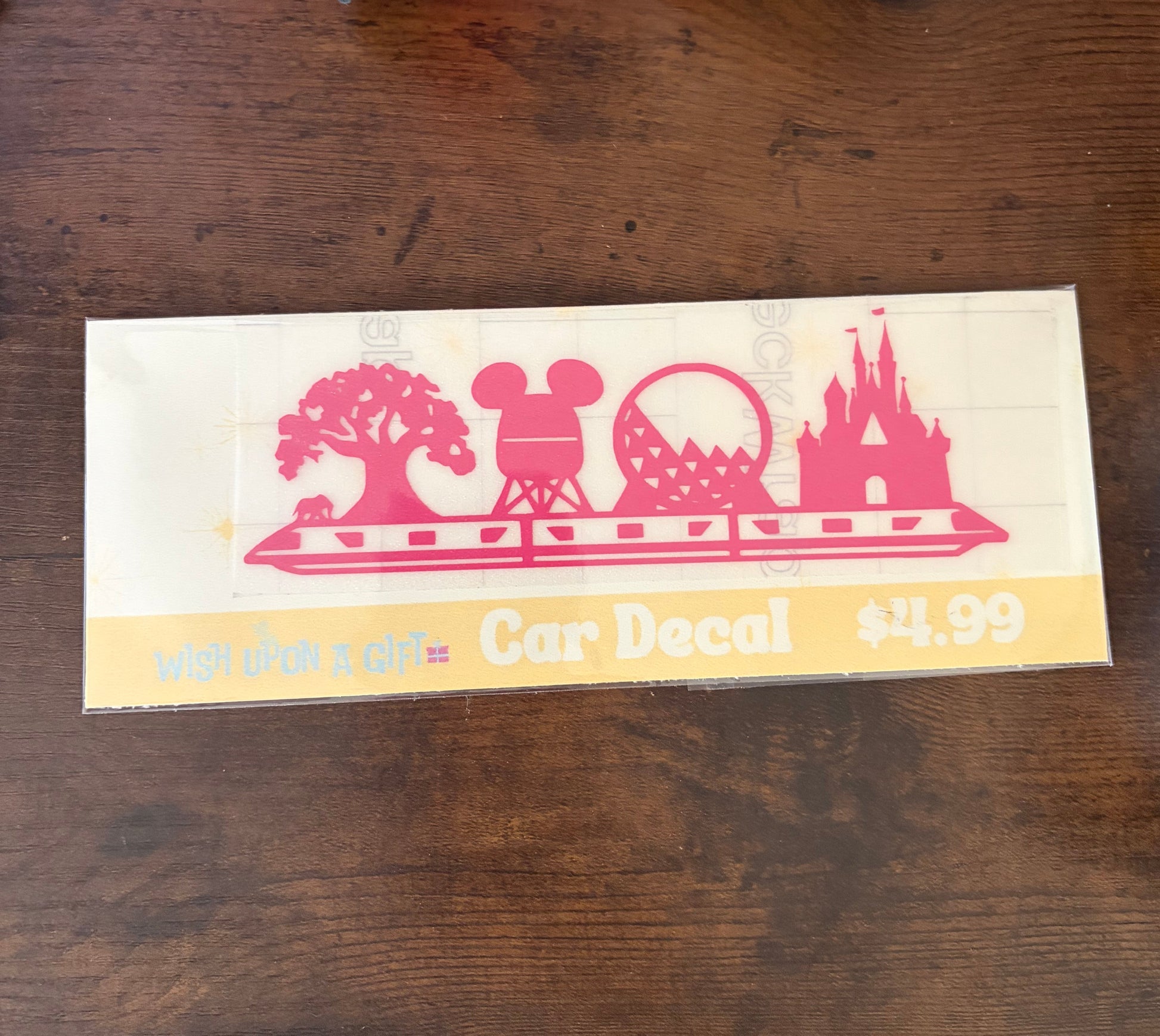 Car decal packaging with graphics of disney skyline and text on a wooden surface