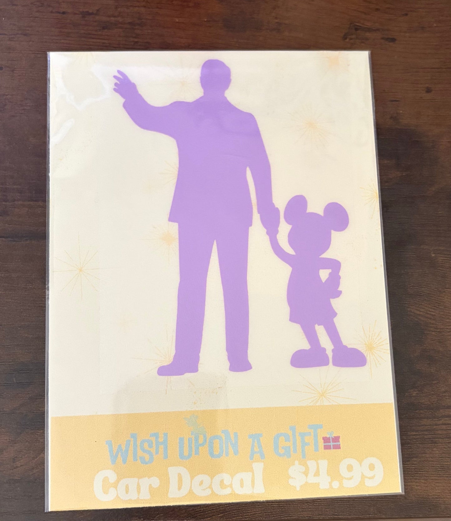 Car decal packaging with graphics of walt disney and mickey mouse and text on a wooden surface