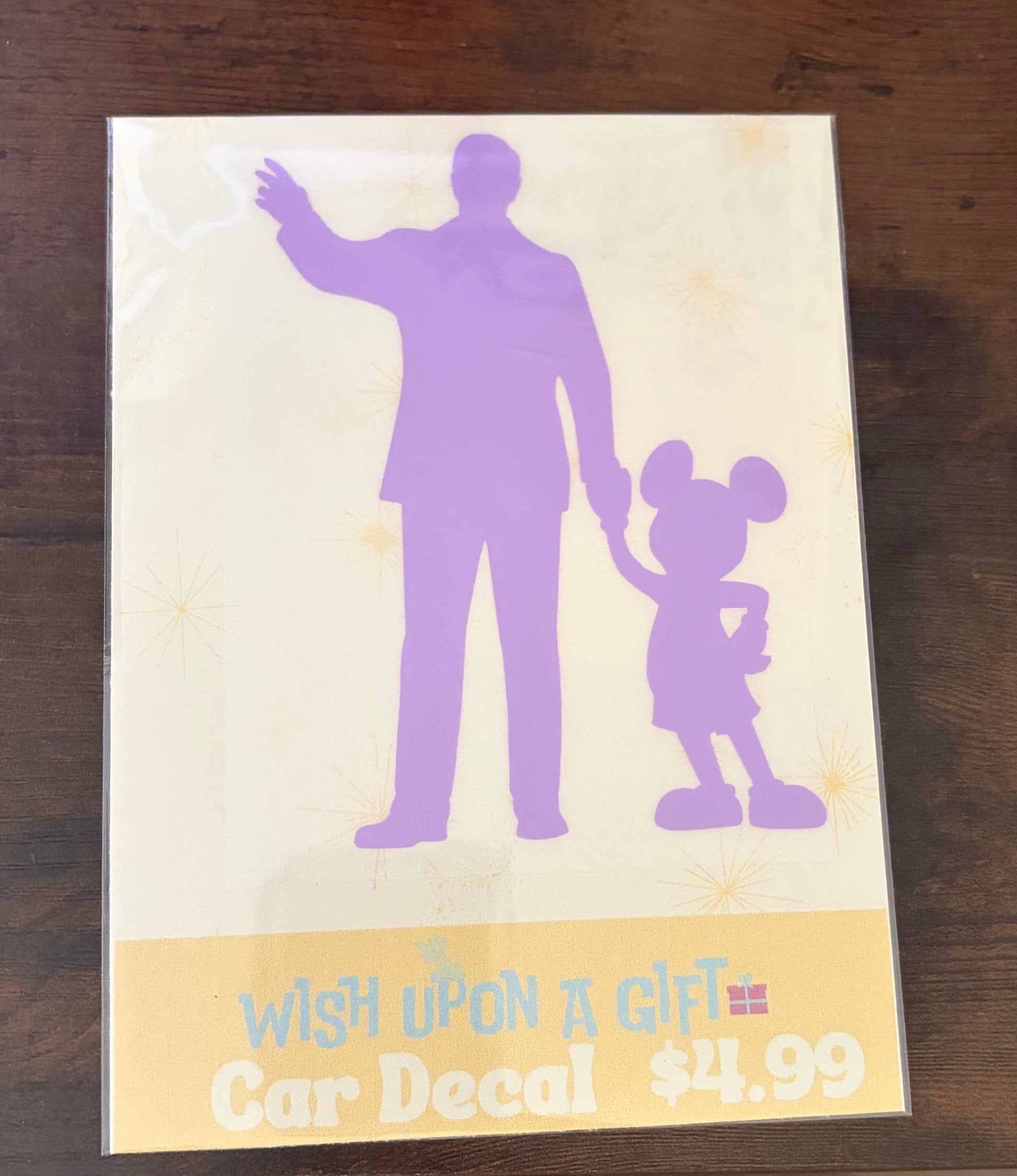 Car decal packaging with graphics of walt disney and mickey mouse and text on a wooden surface