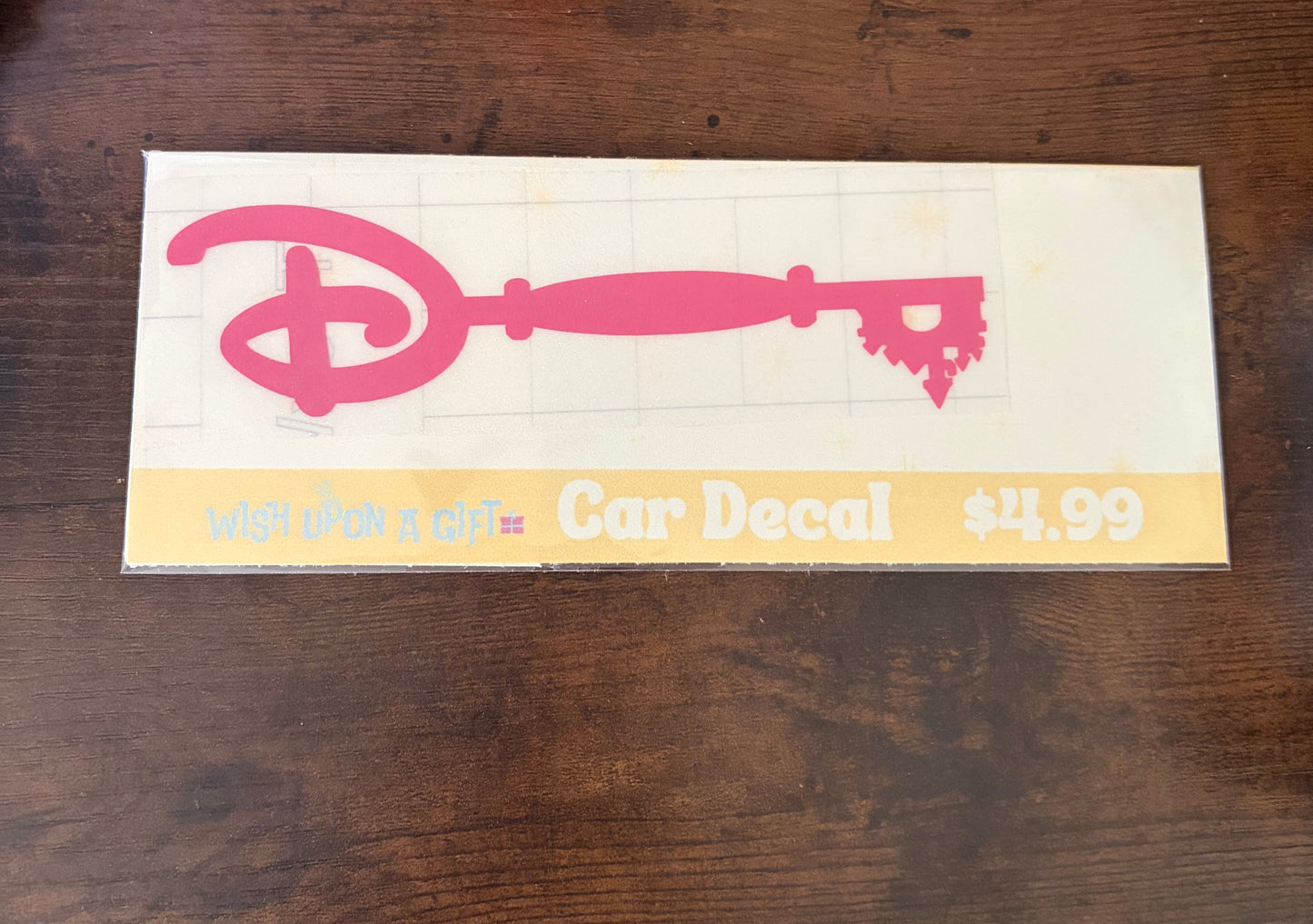 Car decal packaging with graphics of disney key and text on a wooden surface