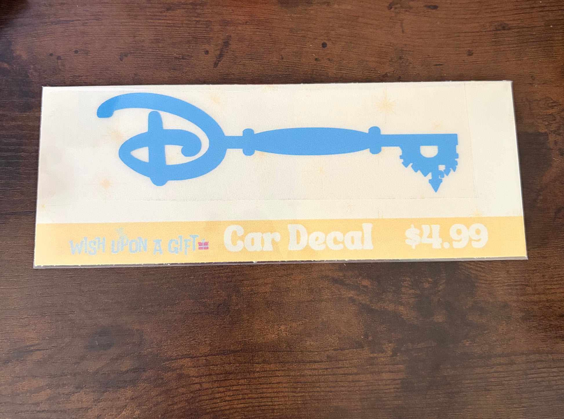 Car decal packaging with graphics of disney key and text on a wooden surface