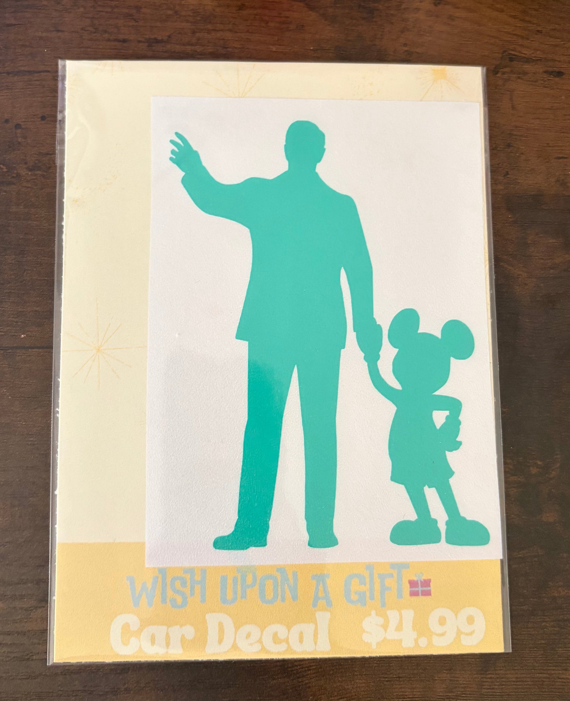 Car decal packaging with graphics of walt disney and mickey mouse and text on a wooden surface