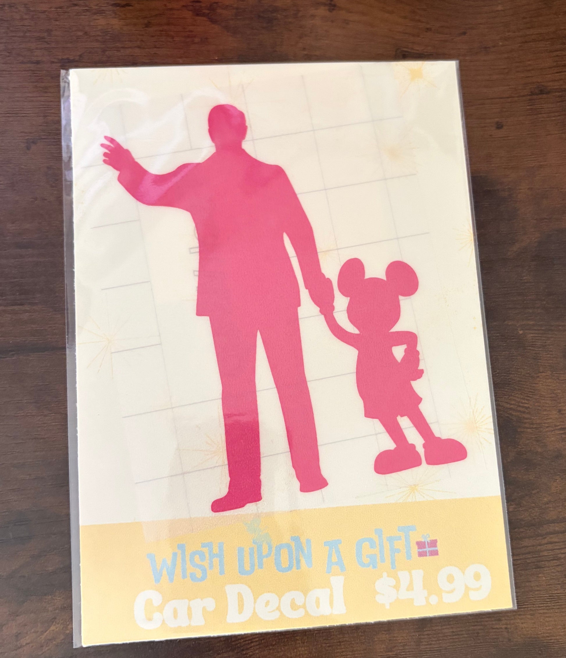Car decal packaging with graphics of walt disney and mickey mouse and text on a wooden surface