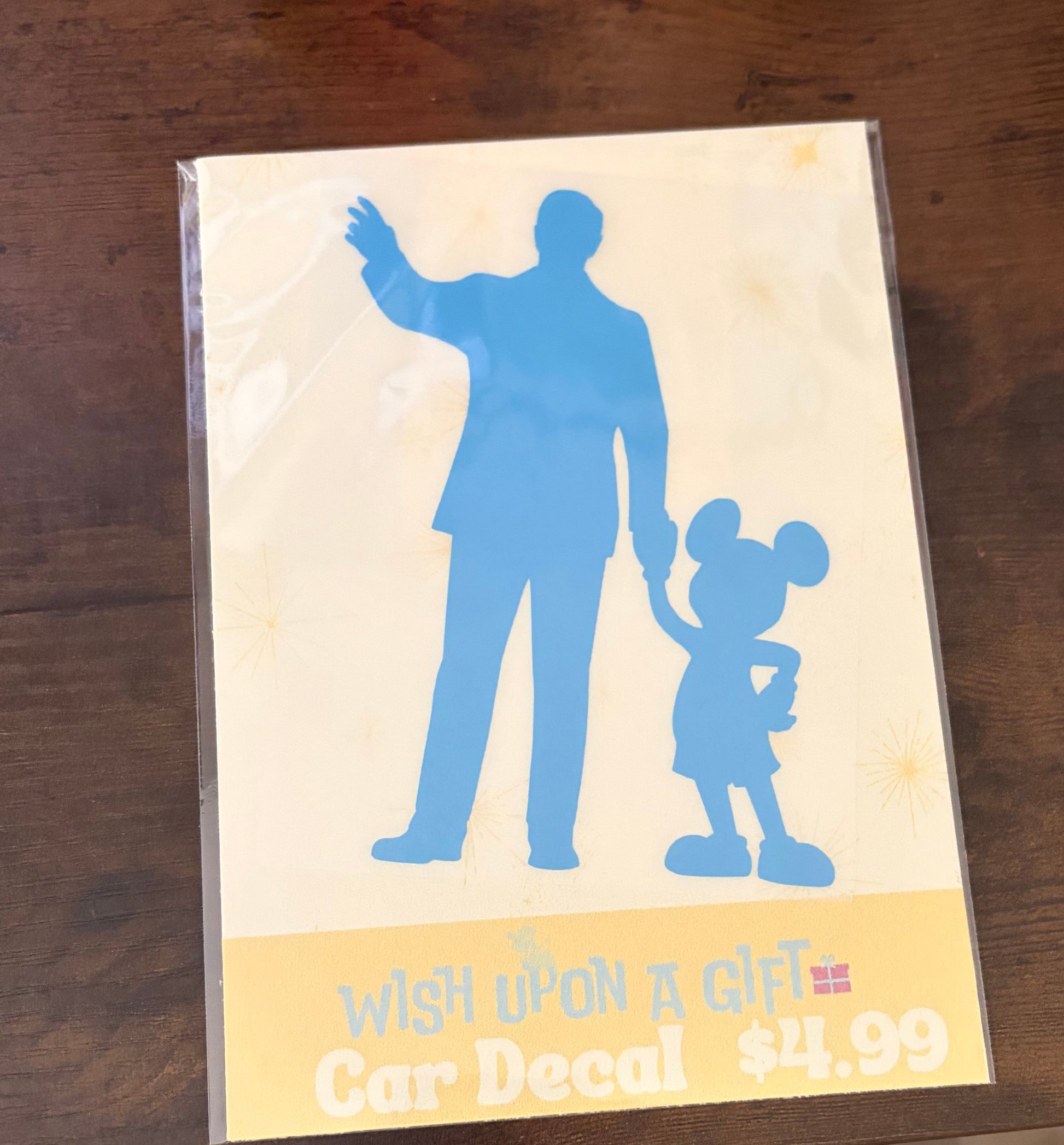 Car decal packaging with graphics of walt disney and mickey mouse and text on a wooden surface