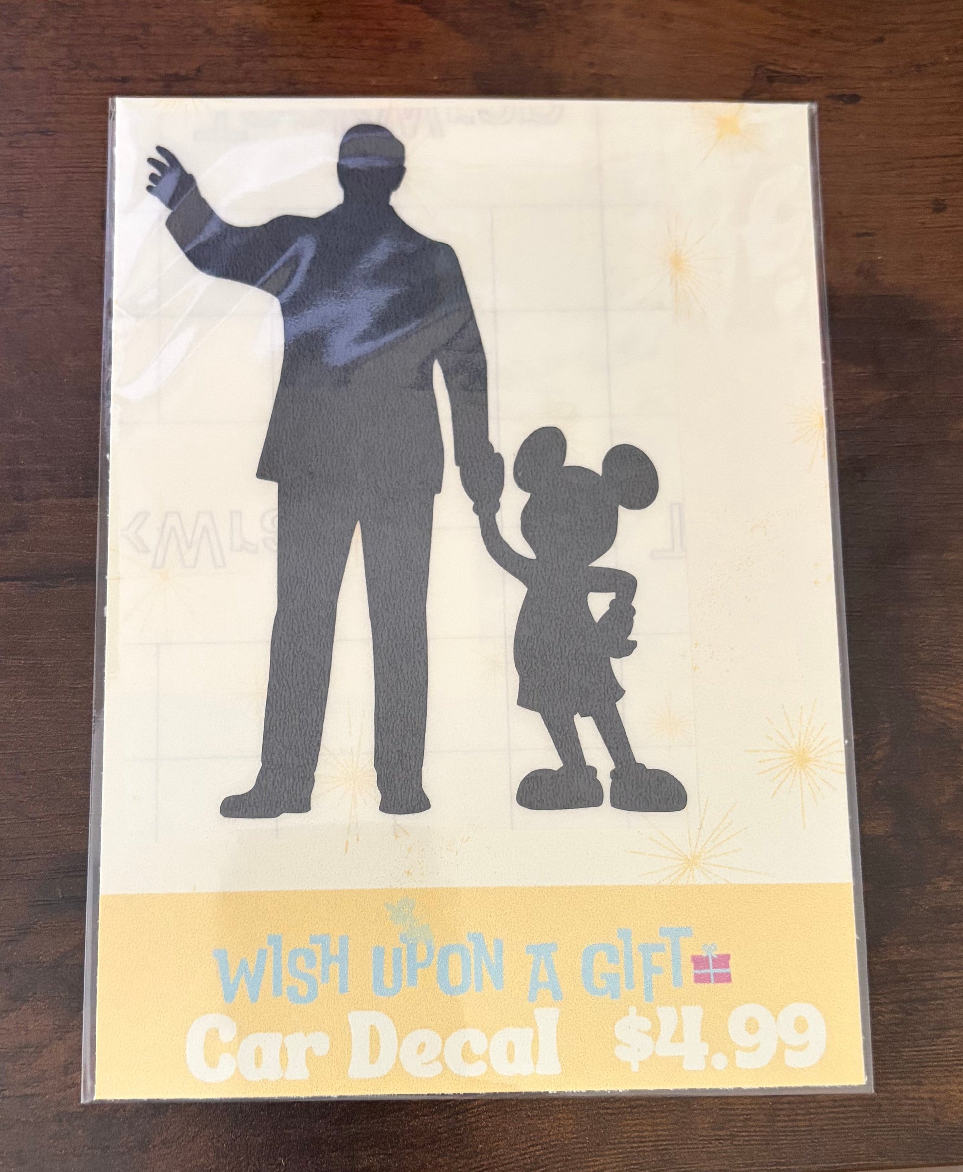Car decal packaging with graphics of walt disney and mickey mouse and text on a wooden surface