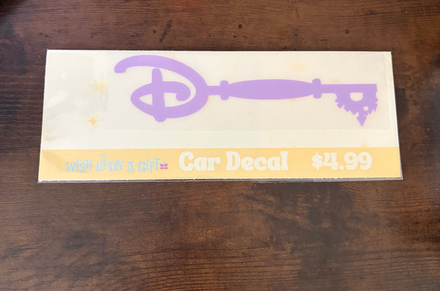 Car decal packaging with graphics of disney key and text on a wooden surface
