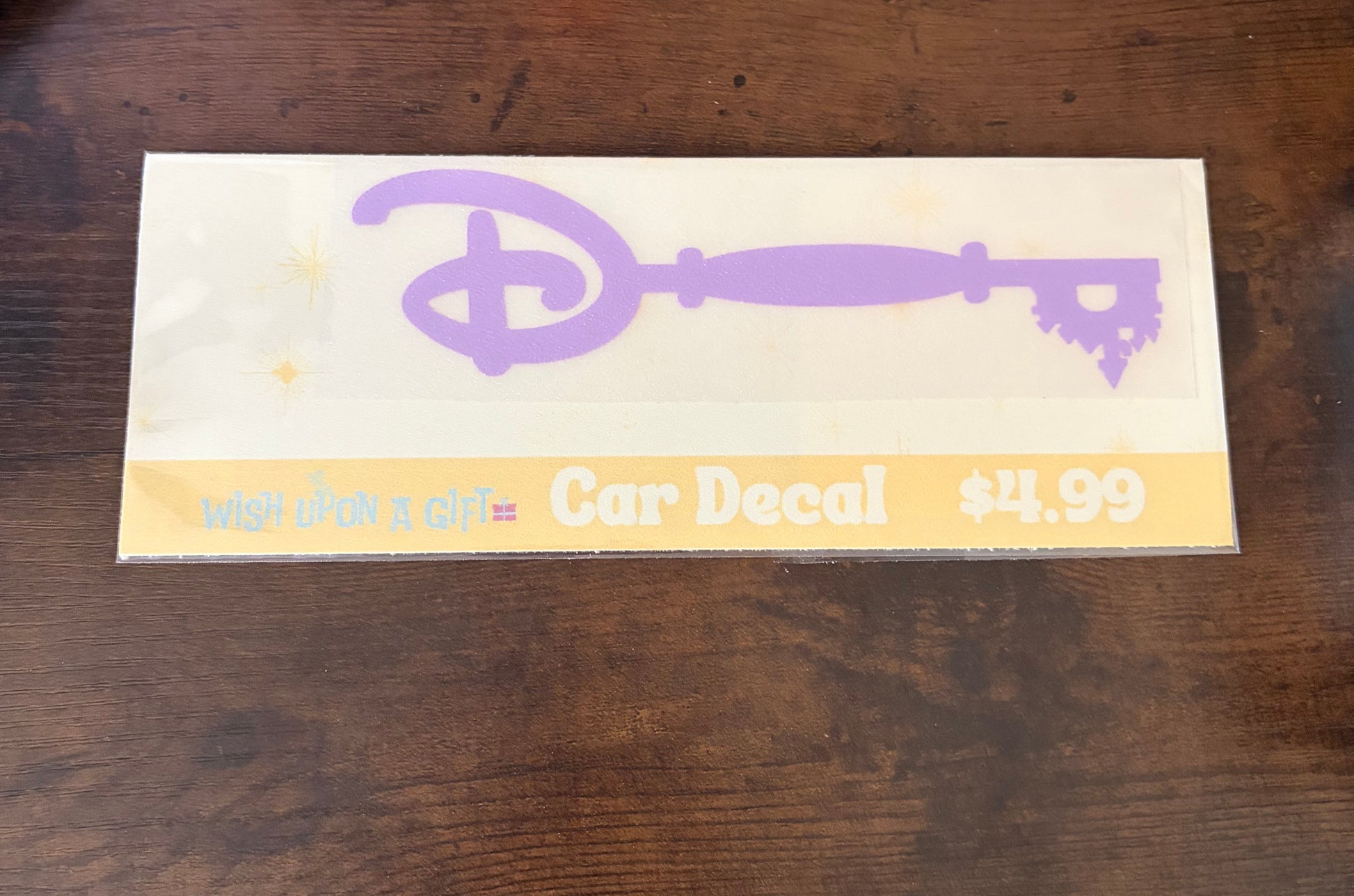 Car decal packaging with graphics of disney key and text on a wooden surface